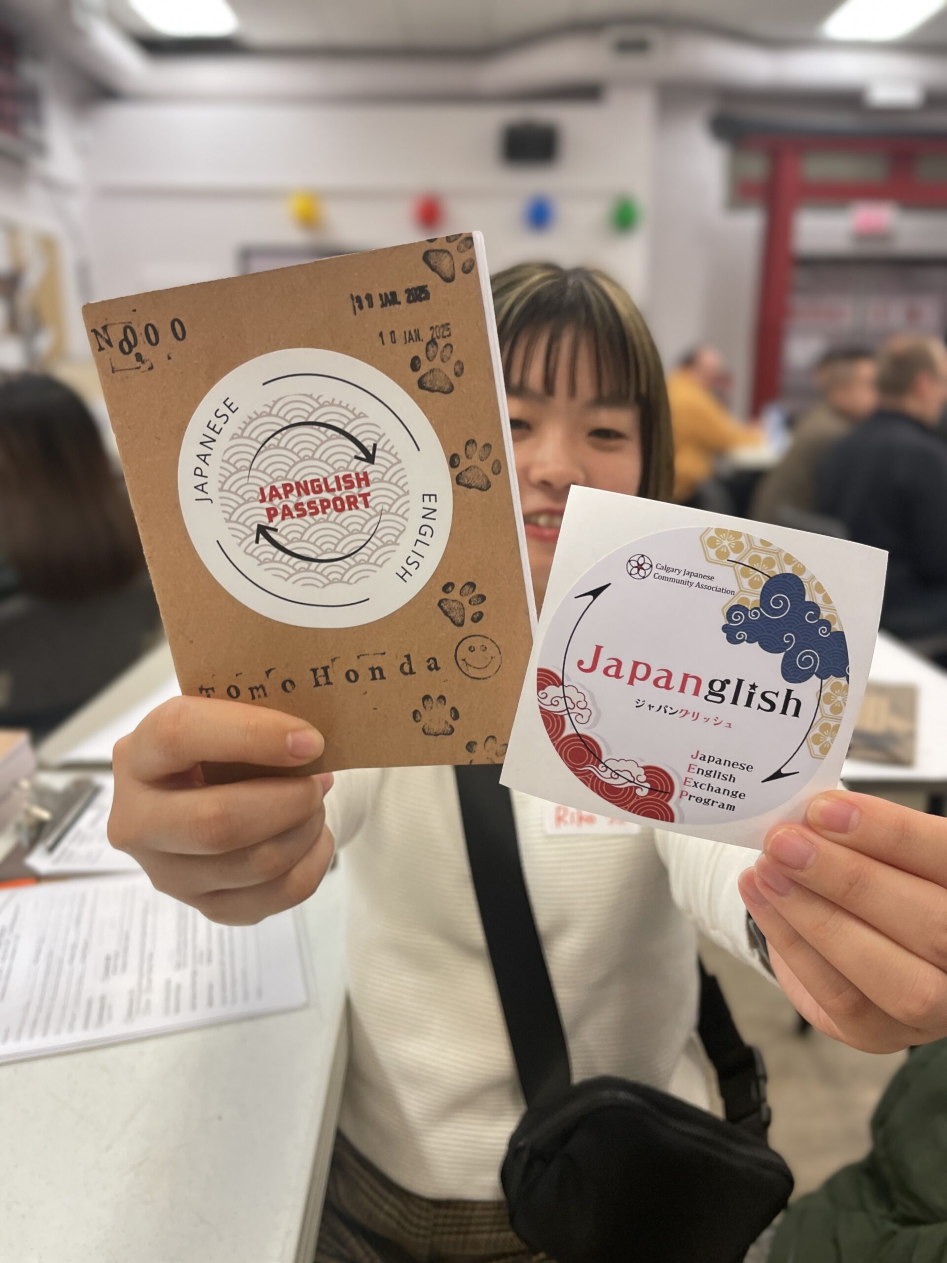 参加者がJapanglishパスポート(スタンプ帳)とJapanglishのステッカーを手に持っている
